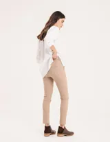 Pantalón chupín color beige de gabardina elastizada con tajitos frontales en el ruedo, pierna recta justa y bolsillos laterales.