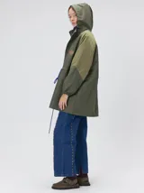 Campera tipo piloto con capucha, cierre frontal con botones y detalle de costuras en zigzag. Presenta cordones ajustables en la cintura y capucha, puños elásticos y logo bordado en el pecho.