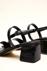 Sandalia de cuero vacuno color negro con textura de cocodrilo, taco cuadrado de 4 cm, punta cuadrada y dos tiras finas, una en el empeine y otra con hebilla en el tobillo.
