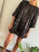 Minivestido negro cubierto de lentejuelas, de corte holgado y manga tres cuartos.