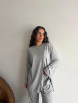 Conjunto de dos piezas color gris melange, confeccionado en tela de lanilla, compuesto por un buzo de manga larga con diseño cruzado al frente y un pantalón largo de corte holgado y tiro alto.