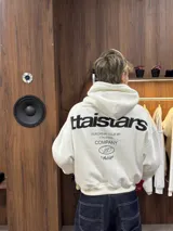 Hoodie de color blanco con capucha, diseño de corte holgado y estampado gráfico en la espalda con tipografía negra.