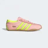 Championes Adidas modelo Tokyo de estilo retro, con exterior de nylon en color rosado y detalles en amarillo neón en las tres tiras laterales y el talón. Presenta una suela de caucho en tono marrón y un diseño de corte bajo.
