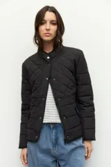 Campera capitoneada color beige, de cuello alto, con bolsillos de solapa y botones metálicos.