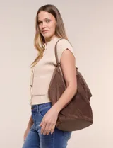 Cartera tipo hobo de gran capacidad color marrón, confeccionada en símil gamuza con base sólida reforzada y ribete de cuerina a juego. Cuenta con asa de hombro y un compartimento interior independiente.