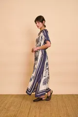 Vestido midi amarillo y blanco con estampado de paisajes y detalles de rayas en el cuello y el dobladillo, de corte holgado, mangas cortas y lazo ajustable en la cintura.