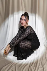 Vestido largo de encaje negro con transparencias, mangas largas y cuello redondo, acompañado de un top y un short interior a juego.