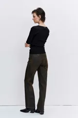 Pantalón de jean estilo wide leg con acabado engomado en tono marrón oscuro. Presenta un corte recto y holgado, con tiro medio y cierre frontal.