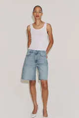 Bermuda de denim color marrón oscuro, de tiro medio y diseño relaxed fit, con cinco bolsillos, trabillas para cinto, bajo desflecado y cierre frontal con cremallera y botón.
