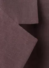 Blazer de lino y viscosa color marrón, de diseño recto, cuello en pico con solapa, mangas tres cuartos, dos bolsillos con solapa, cierre frontal con botones y cinturón integrado a juego.