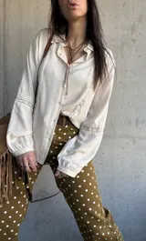 Camisa de manga larga color marfil con detalles de encaje y botones frontales.