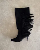 Bota de caña alta confeccionada en cuero vacuno negro, con diseño de flecos laterales y taco fino.