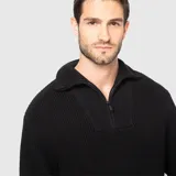 Sweater negro de punto con cuello alto y medio cierre metálico.