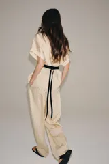 Pantalón de tiro medio Zara Woman Collection, con fajín negro a contraste, pliegues delanteros, pernera ancha, bolsillos laterales ocultos y cierre lateral con cremallera.