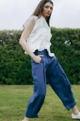 Pantalón azul de lino, de corte ancho y relajado, con bolsillos laterales y detalle de botones en los tobillos.