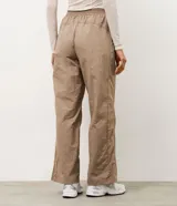 Pantalón deportivo de corte recto confeccionado en microfibra color marrón, con cintura elástica y recortes laterales en tule.