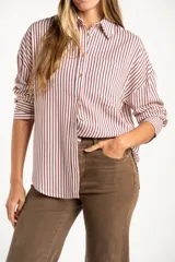 Camisa de corte oversize con estampado de rayas verticales, cuello clásico, cierre frontal con botones y bolsillo en el pecho. Presenta mangas largas con puños abotonados y un diseño fluido.