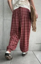 Pantalón estilo babucha color rojo con estampa a cuadros, tiro medio y cintura elástica con cordón ajustable.