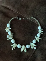 Collar corto de diseño artesanal compuesto por cuentas ovaladas blancas y bastones naturales de nácar intercalados.