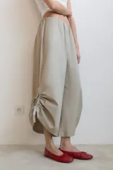 Pantalón tipo culotte de tiro medio con cintura elástica y bolsillos laterales ocultos. Presenta un diseño de pernera ancha con aberturas laterales en el bajo, ajustables mediante cordones con frunces.