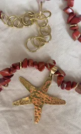 Collar corto con cuentas de piedra color ladrillo y detalles dorados. Dije grande de estrella de mar dorada con textura irregular.