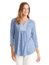 Blusa de modal texturizado en color azul, con cuello a la base y escote en V. Presenta un panel frontal decorado con apliques circulares nacarados y mangas tres cuartos.