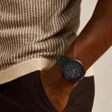 Reloj Fossil Neutra para hombre, con caja redonda de acero inoxidable color negro, esfera negra con números romanos en la posición de las 12 y las 6, agujas plateadas luminiscentes, tres subesferas, indicador de fecha y correa de cuero negro.
