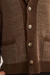 Cardigan marrón tejido con cuello smoking, cierre con botón y bolsillos delanteros.