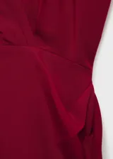 Vestido corto rojo con escote en V cruzado, sin mangas y con detalle drapeado en la falda.