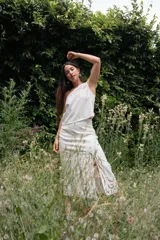 Conjunto blanco de lino, compuesto por un top sin mangas con un solo hombro y detalle de calado, y una falda larga con aberturas frontales y detalle de calado.