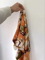 Pañuelo cuadrado de seda con estampado floral en tonos naranja, borra de vino, beige y blanco.