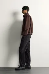 Cazadora bomber de corte regular fit en tejido efecto ante de color marrón oscuro, con cuello alto, cierre frontal de cremallera y bolsillos laterales de vivo.