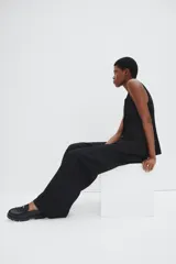 Mocasines tipo penny de cuero sintético negro con suela gruesa track. Presentan un detalle de flecos decorativos en el empeine y una moneda metálica dorada incrustada en la banda frontal.