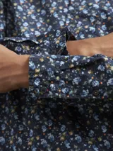 Camisa de hombre azul marino con estampado floral en tonos celeste y amarillo, de manga larga y corte clásico.