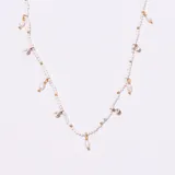 Collar tipo gargantilla con cadena de eslabones dorados, intercalada con cuentas blancas y dijes colgantes: perlas irregulares, cristales redondos engarzados y pequeñas cuentas doradas.