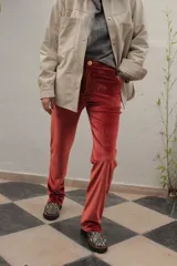 Pantalón de terciopelo color naranja, de corte recto y tiro medio con cierre frontal de botón y bolsillos.