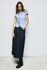 Falda midi de denim azul oscuro con tiro medio, bolsillos delanteros y costuras a contraste. Presenta un diseño con canesú estructurado y falda con frunces, cierre frontal con cremallera y botón metálico.
