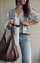 Chaleco de denim celeste con bordados detallados y apliques de brillos en la parte frontal.