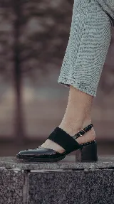 Zapato de taco ancho y medio, color negro, confeccionado en cuero. Presenta diseño destalonado con tira ajustable en el talón, faja ancha de gamuza sobre el empeine y puntera fina de charol.