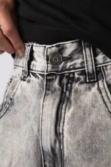 Bermuda de jean de corte mom, estilo carpintero, con lavado ácido gris claro. Presenta costuras marcadas, bolsillos funcionales y detalles de refuerzo en los laterales.