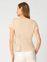 Remera blanca de manga corta con cuello redondo, confeccionada en una mezcla de modal, poliéster y elastano. Presenta un diseño con alforzas verticales en el frente que aportan estructura y una silueta relajada.