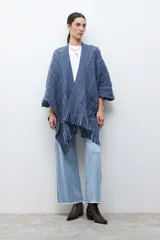 Ruana de punto color azul con estampado de espiga en dos tonos de azul, diseño holgado, con bolsillos y flecos en el borde inferior.