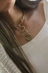 Gargantilla rígida dorada con dije colgante formado por tres círculos y una espiral.