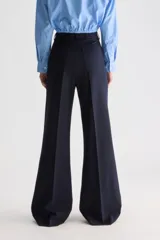 Pantalón azul marino de tiro alto y calce ajustado con diseño acampanado. Presenta bolsillos aplicados en el delantero y cierre frontal.