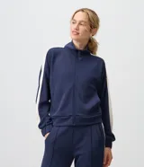 Campera deportiva de microfibra azul marino con cuello alto, cierre frontal y franjas blancas en contraste a lo largo de las mangas.