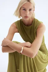 Vestido tobillero de punto color verde oliva, con escote redondo, manga japonesa y cuerpo entallado con costuras laterales fruncidas para un efecto drapeado. La falda tiene una caída suave y una costura diagonal fruncida en la cadera. Forrado.