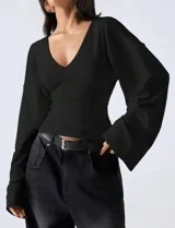 Blusa negra de calce entallado con escote en V y mangas largas amplias tipo campana. Confeccionada en tela suave y liviana con caída fluida.