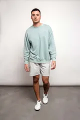 Buzo verde agua liso, de corte oversize, confeccionado con 60% algodón y 40% poliéster.