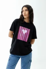 Remerón negro de corte oversize con estampa de corazón derretido sobre fondo de rayas rosas y rojas.