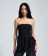 Blusa peplum sin tirantes de color negro, confeccionada en bengalina con diseño asimétrico en el dobladillo.